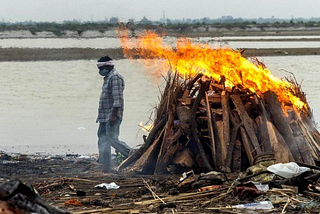 A person cremating a dead body at the shore of Ganges