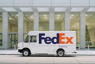 FedEx truck in front of a building with a Christmas tree inside