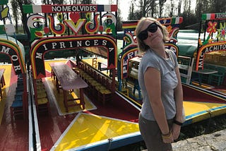 The author doing a faux-elegant pose in front of a colourful boat that’s set up like a bar.