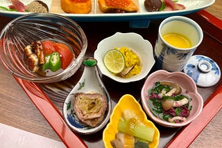 Artistically arranged Japanese food in seven small dishes.