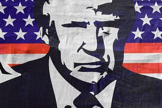 Cartoon image of Donald Trump in front of the American flag, with the caption “American Psycho”.