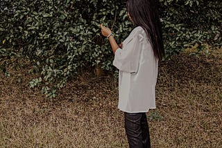 Author standing beside a tree wearing a white clothing and black pant