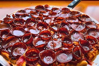 A pizza covered in Old World style pepperoni that cups and chars when baking.