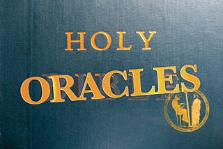 Photo of a bible that has a blue cover with gold type. I have superimposed “ORACLES” over BIBLE at a slight angle and placed a graphic stamp of an oracle reading that appears to have been on a round Egyptian plate. ~ Wikimedia Commons