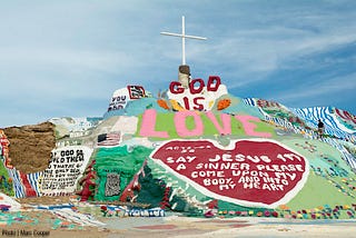 Uma montanha colorida com uma cruz no topo. Abaixo da cruz está escrito bem grande “God is love” e abaixo há um grande coração, dentro dele a frase “Acts 2 36 say Jesus im a sinner please come upon my body, and into my heart” (sic). Outras imagens e frases menores em inglês colorem a montanha.