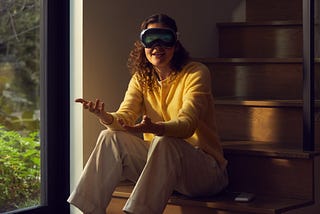 A young woman sitting on a stair using Vision Pro
