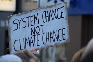 a sign saying system change, not climate change