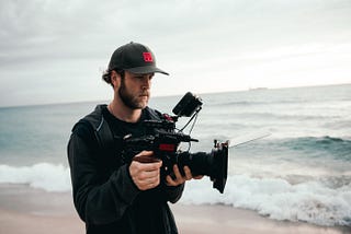 Man filming a scene on the beach.