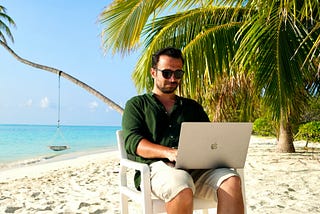Man working on laptop as a one-person business by the beach