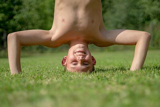 boy stands on his head in grass
