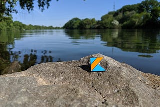 Kotlin logo top of rock near river and trees