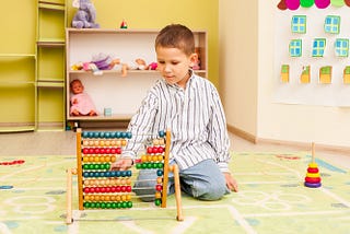 Cute preschooler child boy playing with wooden color abacus in Plainfield. The educational games