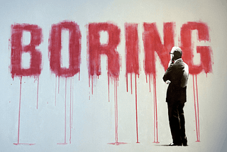 Boring written and dripping red down a wall as a man looks on