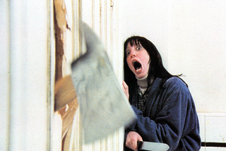 Shelley Duvall in the Shining as Wendy is terrified as an axe comes through the door. The Shining, Stephen King, Anne Hall, Kubrick, haunted hotel, Overlook, horror film, score, film, cinema, history, World Cup, soccer, Taylor and Justin, wedding, wedding dress, 250, where is, who is Shelley Duvall?