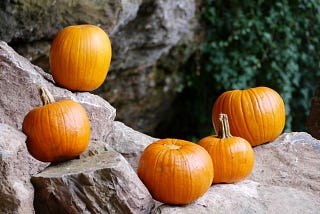 Five pumpkins arranged on some large boulders.