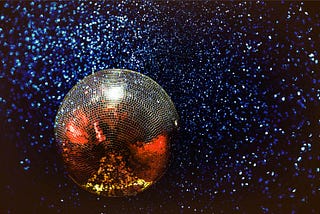 A discoball surrounded by magical blue sparkles