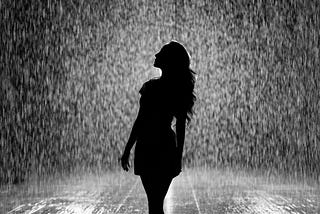 Silhouette of woman in white shower of rain on a road.