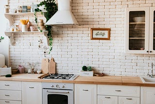 A light airy kitchen, with white brick walls and white cabinets.
