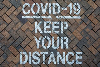 photo of covid-19 keep your distance; text on pavement posted on Dr. James Goydos 2021 article on New Jersey public health measures