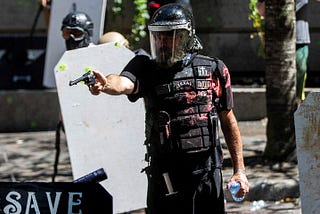 Image shows Alan Swinney in armor and helmet, glaring through mask. His armor is covered in paint and in his right arm he aims a pistol.