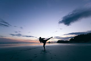 Figure in karate pose on beach at sunset