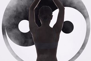 A woman doing yoga in front of a yin/yang symbol