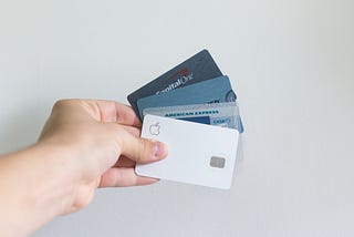 A hand holding 4 credit cards from various credit providers