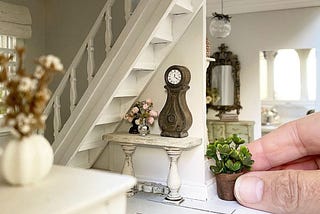 Hand carefully placing furniture in a dollhouse