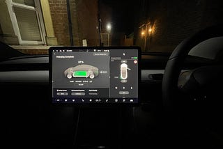 Photo of the Model 3 infotainment system at night with a house behind it
