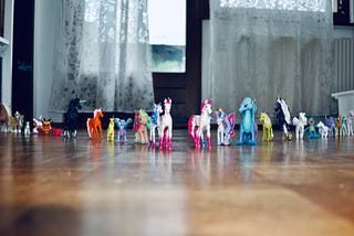 Image by author of small toy action figures including unicorns arranged in a line.