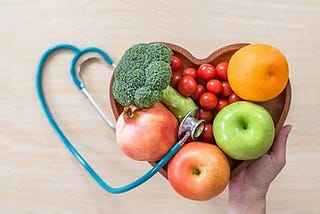 heart shaped bowl filled with fruits & veggies and stethoscope in the shape of a heart