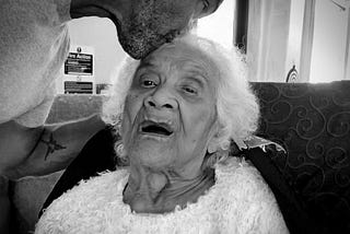 The author kissing his elderly mother goodbye on her forehead.