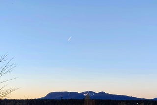 A meteor or a possible space re-entry in the evening sky over the mountains.
