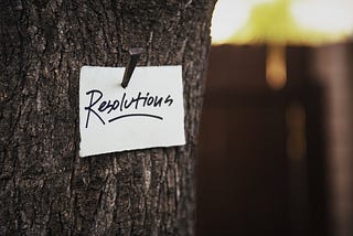 A note that says “resolutions” is nailed to a tree