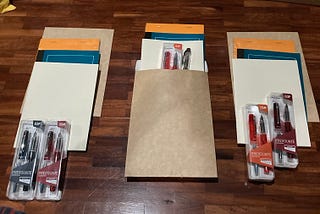 Kraft envelope, a pair of Platinum Prefounte pens, a Rhodia notepad, a Livenotes notebook, and a Midori notebook.