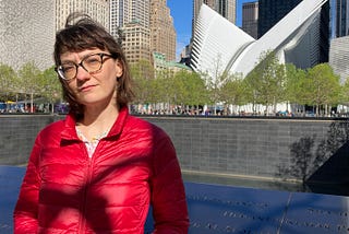 Photo of the author in a red jacket, standing in front of the 9/11 Memorial