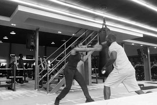 A picture of a girl throwing a jab at her coach during boxing training