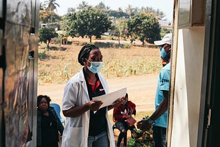 A masked healthcare worker is going door-to-door to deliver healthcare services in Mozambique.