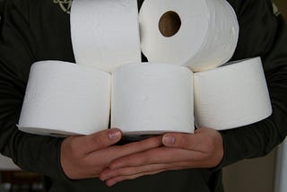 Person holding a stack toilet paper