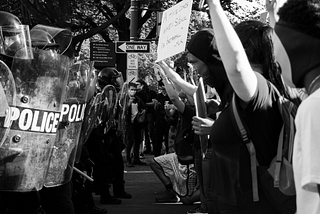 black and white picture of riot-looking police head to head with protestors