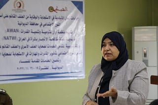 Photo of Feryal Alkaabi, Director of Awan Organization. She is standing, speaking in front of a white board, wearing a headscarf.