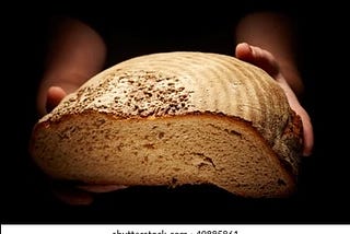 A woman’s hands holding half a loaf of bread