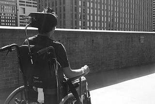 Ather sitting on a wheelchair facing the Philly skyline. The photo is taken from behind.