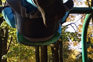 Person on park swing, feet and lower half of body mid-upward move