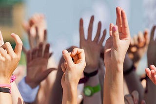 Lots of raised hands, suggesting the people are voting for something