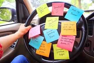 woman holding car steering wheel that is covered in post it notes