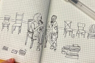 Illustration of two men sitting and talking with five empty chairs in the background