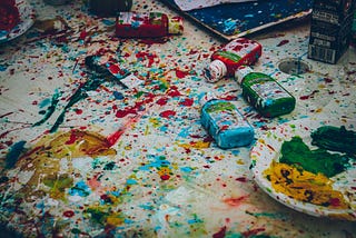 Splattered paints with a palette and art supplies.