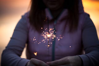 Woman holding sparkler as it burns down