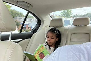 Photo of the author’s daughter reading a Martin Luther King Jr. book in the car.